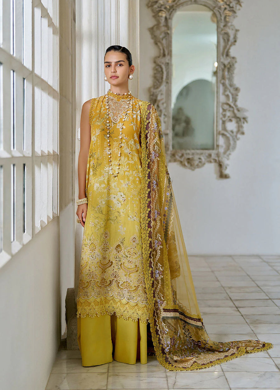 Front view of a woman wearing an elegant mustard yellow embroidered lawn suit with floral patterns, pearl embellished high neck, and matching straight pants, holding a sheer embroidered dupatta with scalloped lace edges.