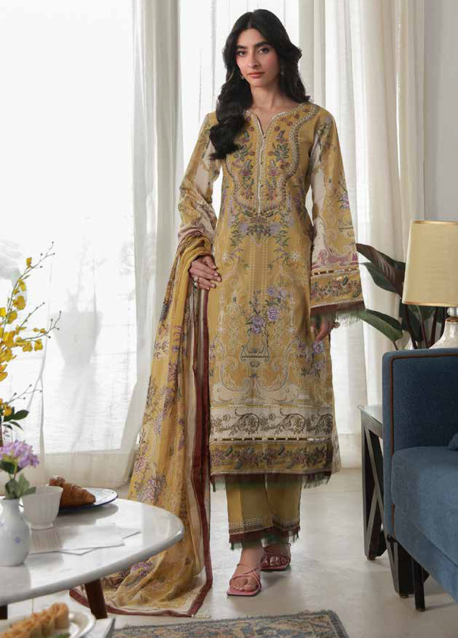 Woman wearing a mustard floral printed lawn shirt with detailed embroidery on neckline, holding a matching printed chiffon dupatta in living room setting.