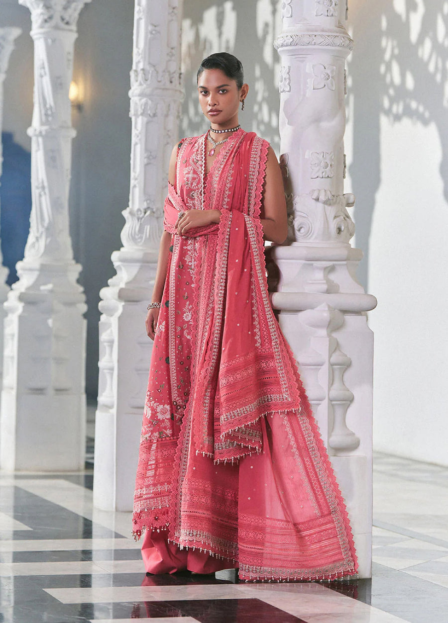 Close-up of woman in pink embroidered lawn suit holding matching lace-edged dupatta beside white intricately carved pillars.
