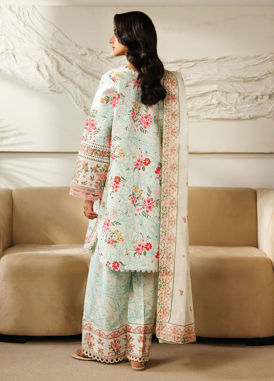 Back view of a woman showcasing the floral embroidered lawn suit with matching trousers and a dupatta featuring detailed floral borders, standing in a neutral room.