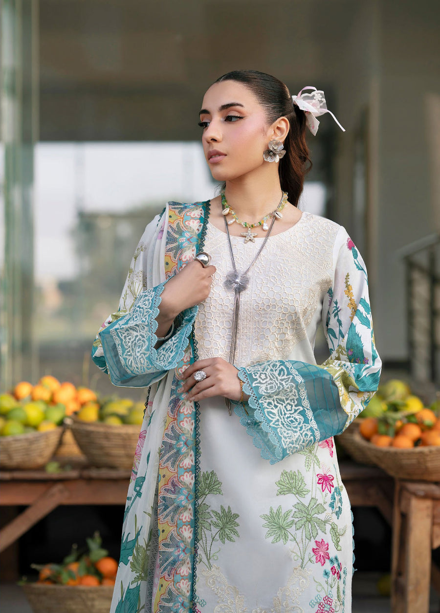 Close-up front view showing intricate embroidery on neckline and floral patterns on sleeves of white lawn suit with teal lace borders, woman accessorized with silver jewelry.