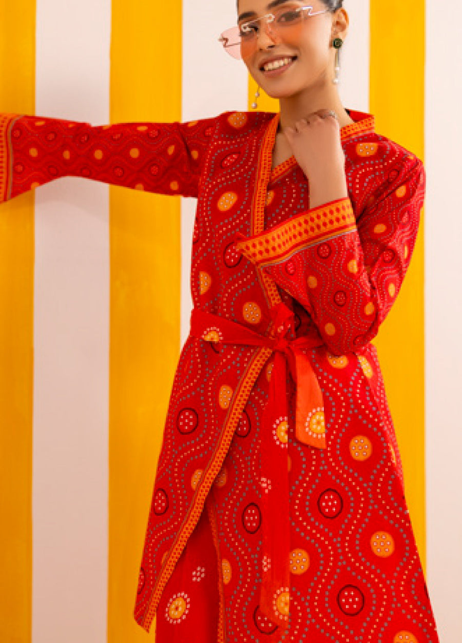 Close-up of woman in red printed lawn suit with wrap style shirt tied at waist with belt, highlighting detailed fabric pattern and cuff design