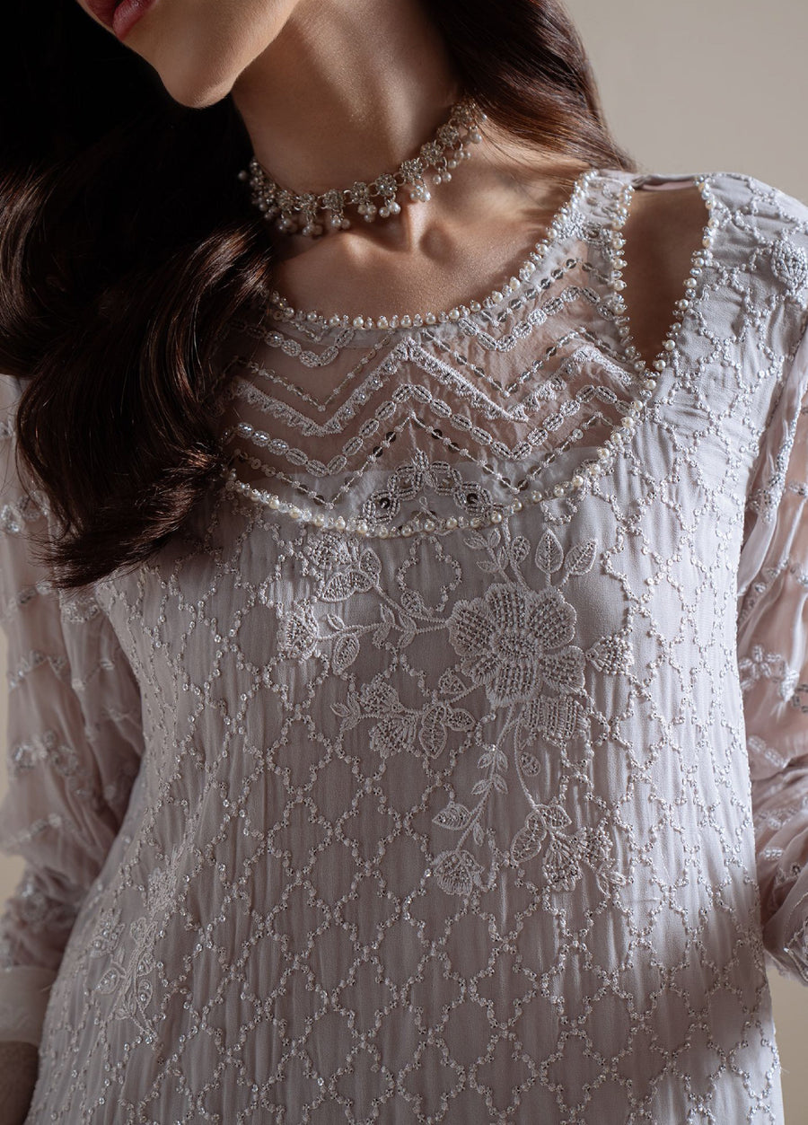 Detailed close-up of haute couture embroidery on the neckline and shoulder of the chiffon tunic, featuring floral motifs and pearl embellishments