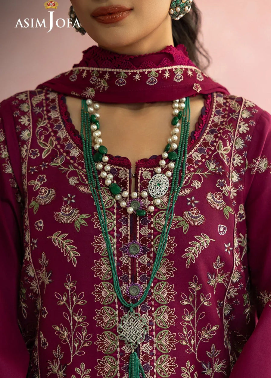 Close-up detail of floral embroidery on magenta fabric and scalloped hem of matching pants showing craftsmanship and fabric quality.