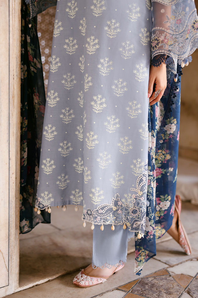 Detailed close-up of silver floral embroidery and scalloped hem on sky blue lawn shirt paired with embroidered trousers