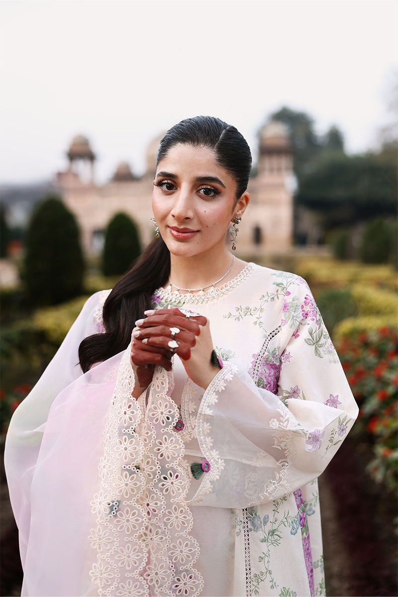 Woman smiling while holding the sheer dupatta featuring scalloped flower lace trim and subtle bead embellishments against floral suit background.