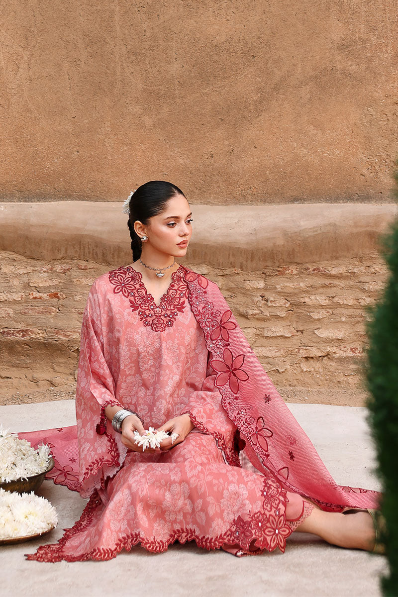 Woman seated wearing a modest pink embroidered lawn suit with a matching embroidered dupatta draped over her shoulder.