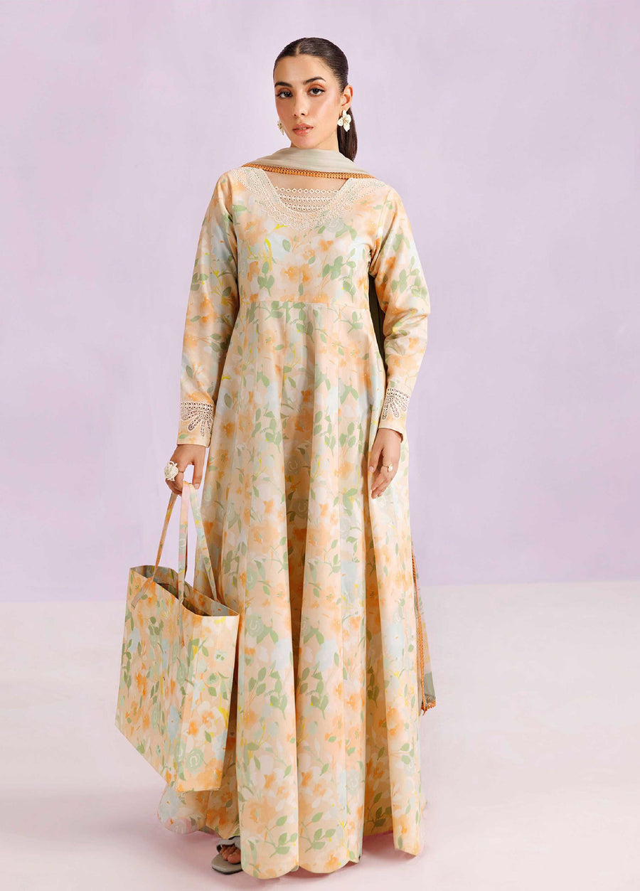 Woman wearing a flowing embroidered floral lawn suit in peach and green, holding a matching floral printed tote bag, standing against a light purple background.