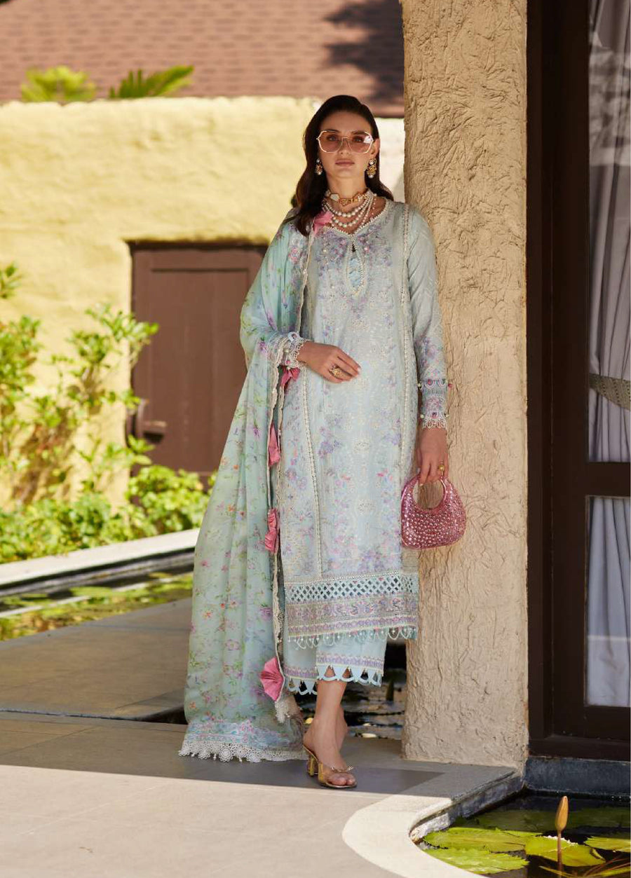 Woman wearing an embroidered pastel blue lawn suit with floral patterns, lace detailing, and matching dupatta holding a pink beaded handbag