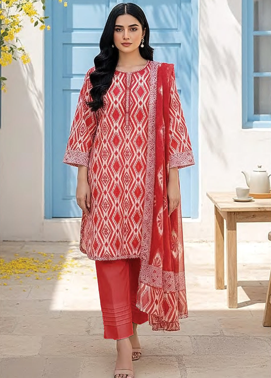Woman wearing a red and white geometric printed lawn shirt with matching red trousers and a printed lawn dupatta, standing outdoors near a blue door.