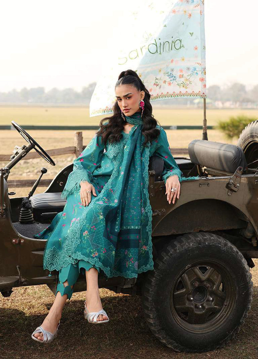 Woman seated on side of vintage military jeep wearing teal embroidered lawn suit with matching lace-trimmed dupatta and silver sandals