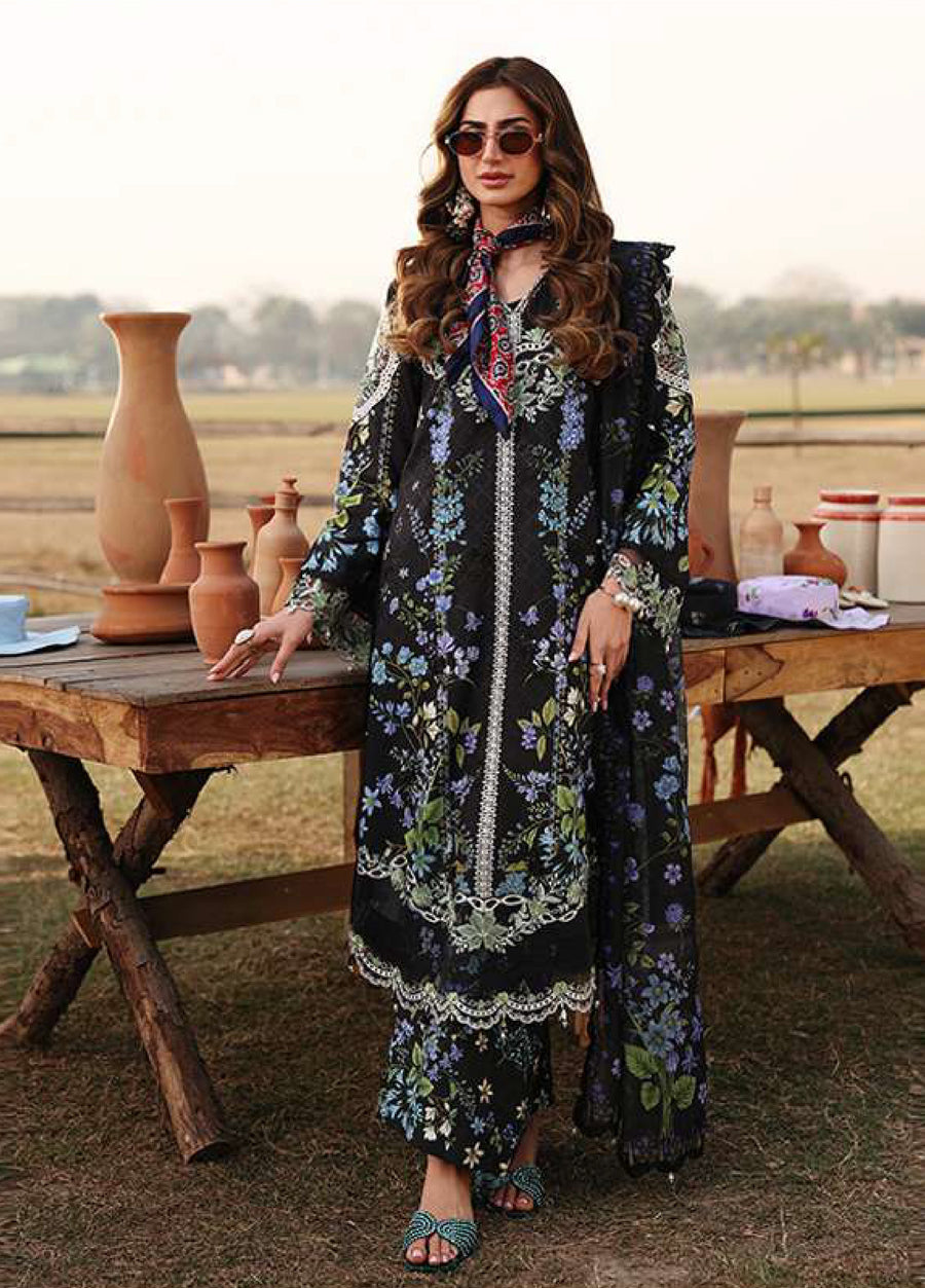 Front view close-up of woman in a black floral embroidered lawn suit accessorized with rings and a scarf at neckline.