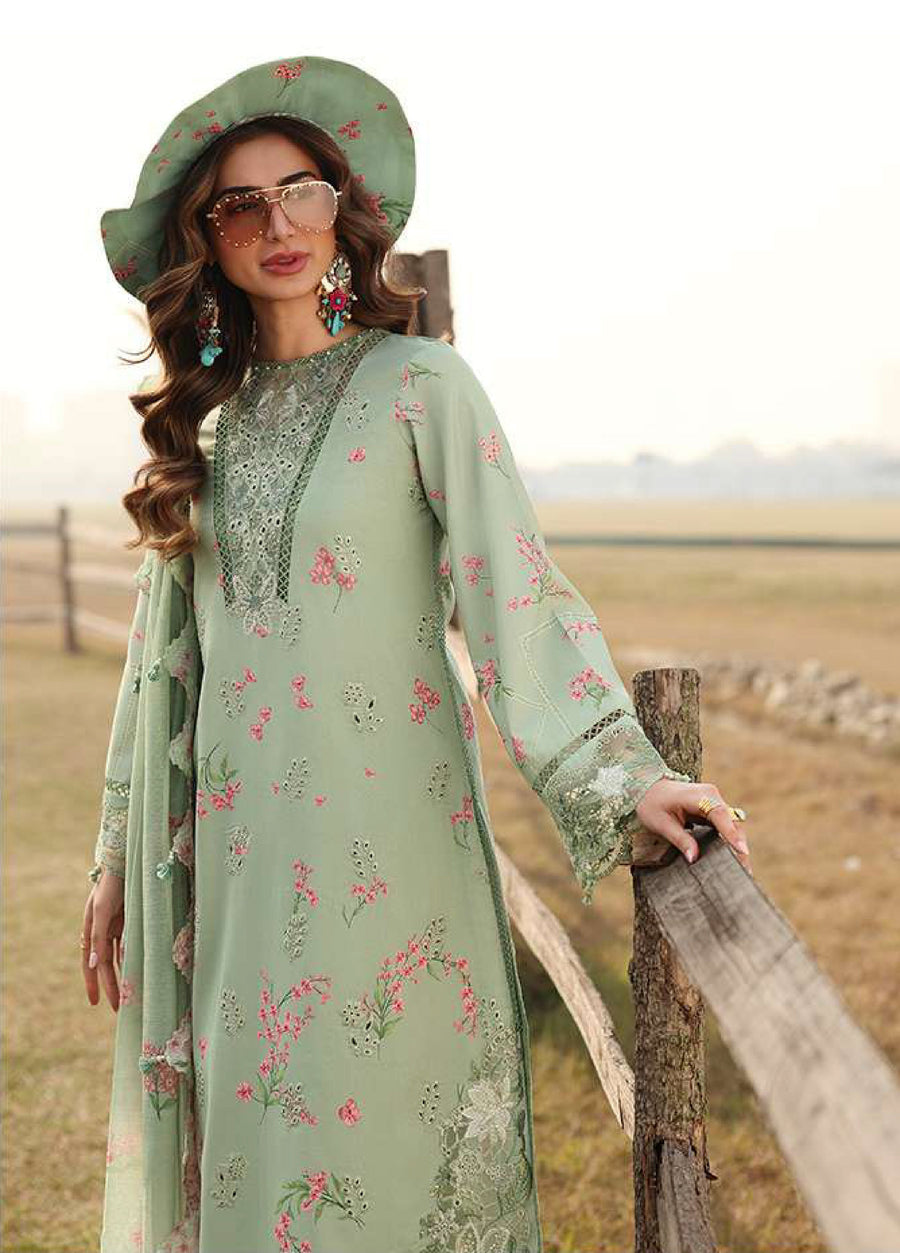 Close-up of a woman showcasing detailed floral embroidery on the neckline and sleeves of a pastel green lawn suit with matching dupatta.