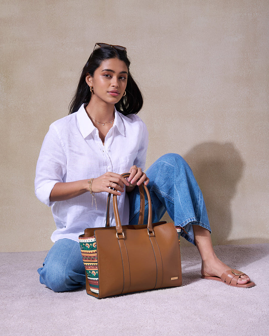 Model sitting on floor holding Kenya Tote bag, styled with casual white top and jeans