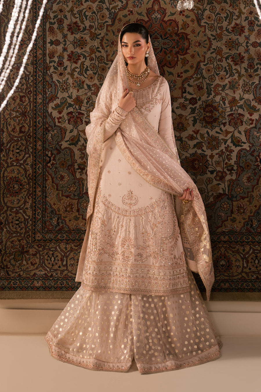 Close-up of hands holding embroidered handbag with detailed beadwork and intricate floral embroidery matching sharara set