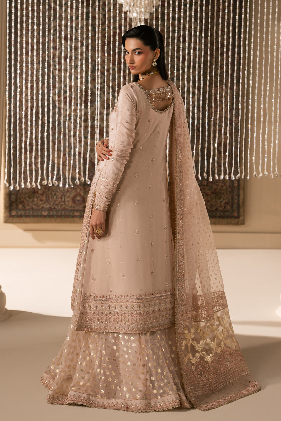 Back view of pale peach sharara set showing embroidered long shirt with detailed border and gold foil sharara pants