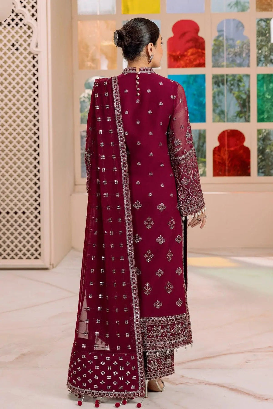 Back view showing embroidered details and button closure of magenta traditional suit