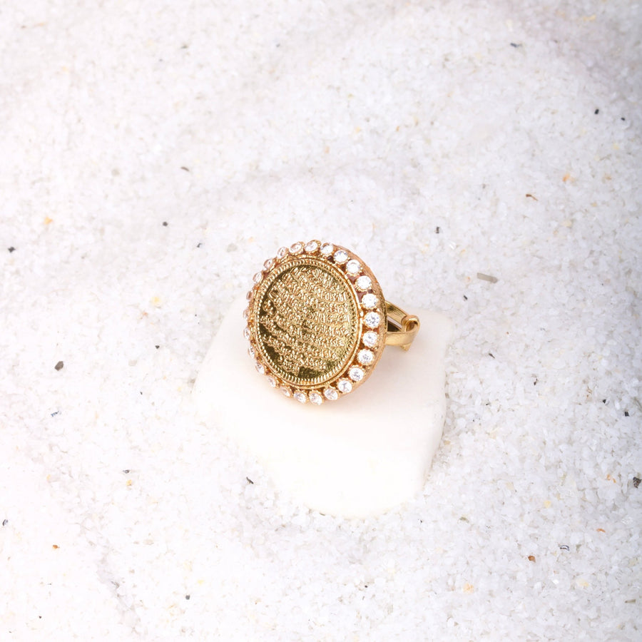Ayut-Ul-Kursi ring positioned on white sand with a clear view of gold engraving and surrounding stones