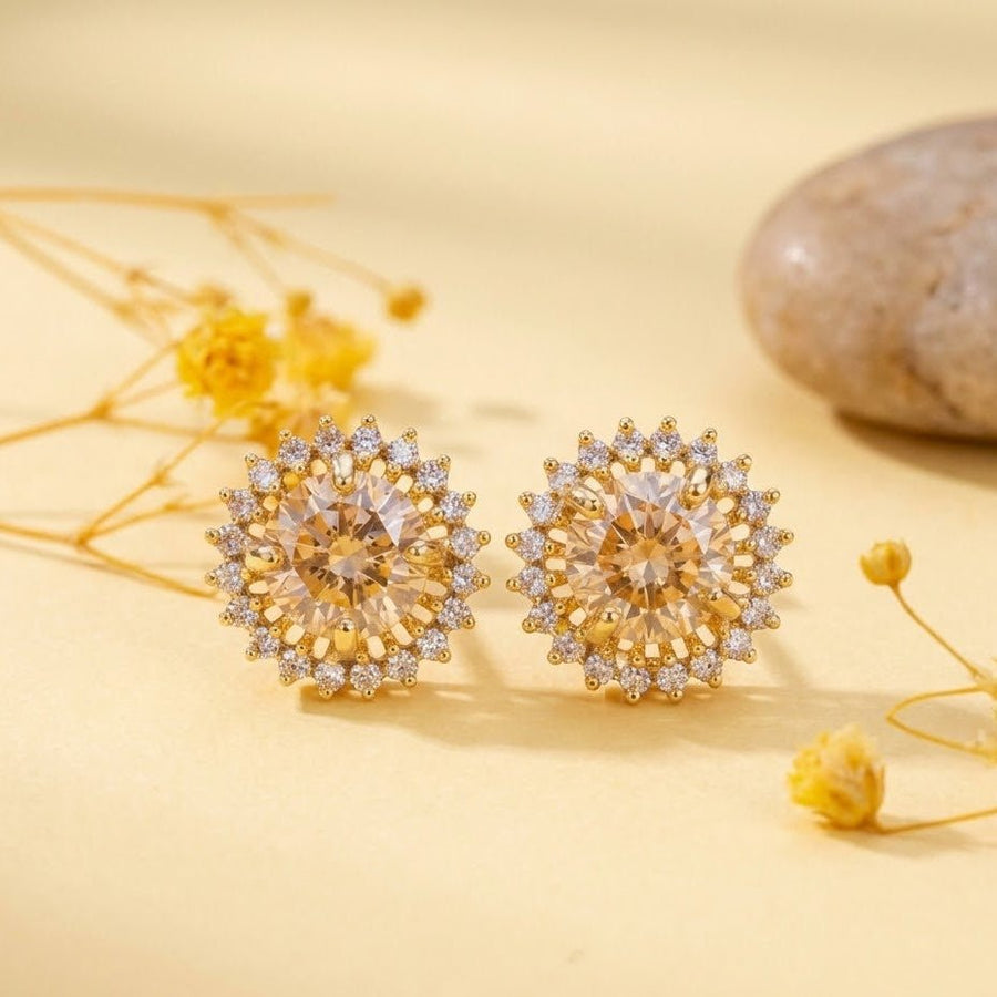 Champagne gemstone halo stud earrings displayed on a yellow surface with dried flowers