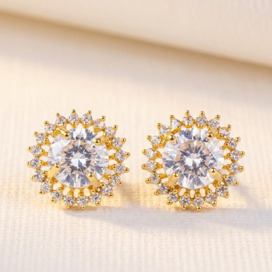Clear gemstone halo stud earrings displayed on soft beige fabric under warm light