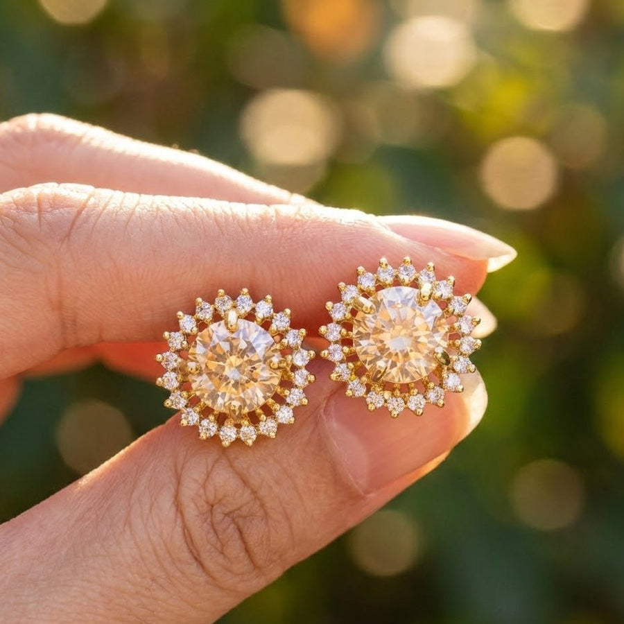 Hand holding champagne gemstone halo stud earrings showing light reflection