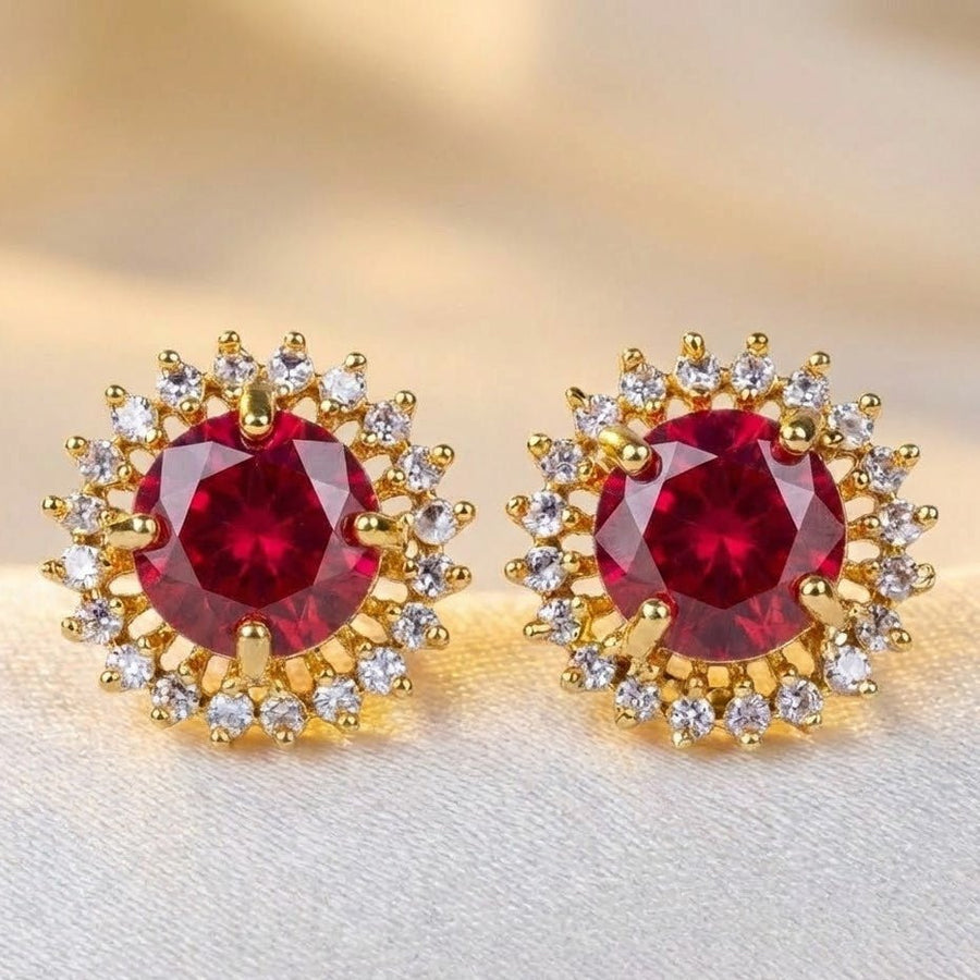 Red gemstone halo stud earrings displayed on textured beige fabric