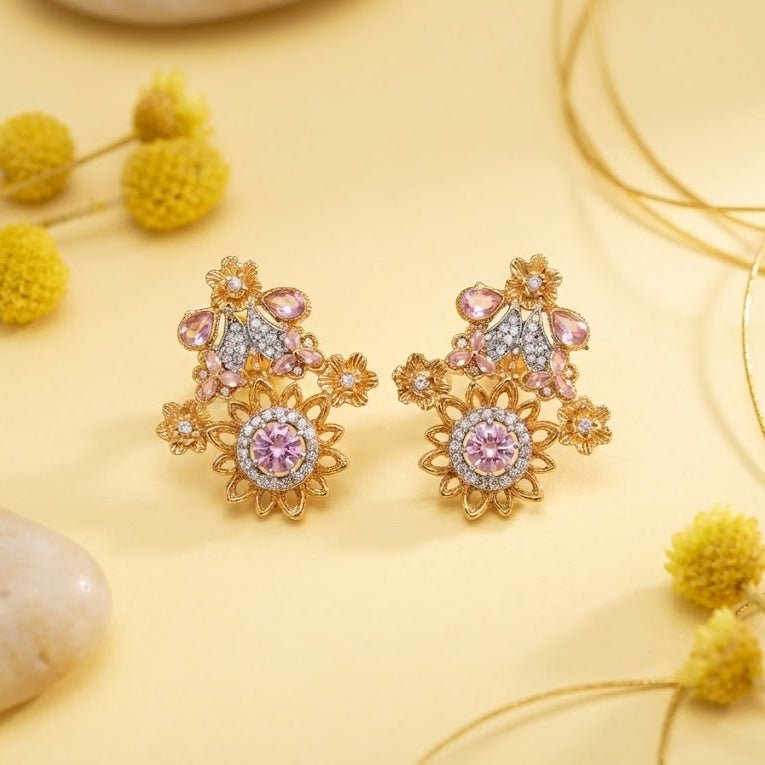 Blue gemstone floral earrings resting on a soft white textured background under warm ambient light