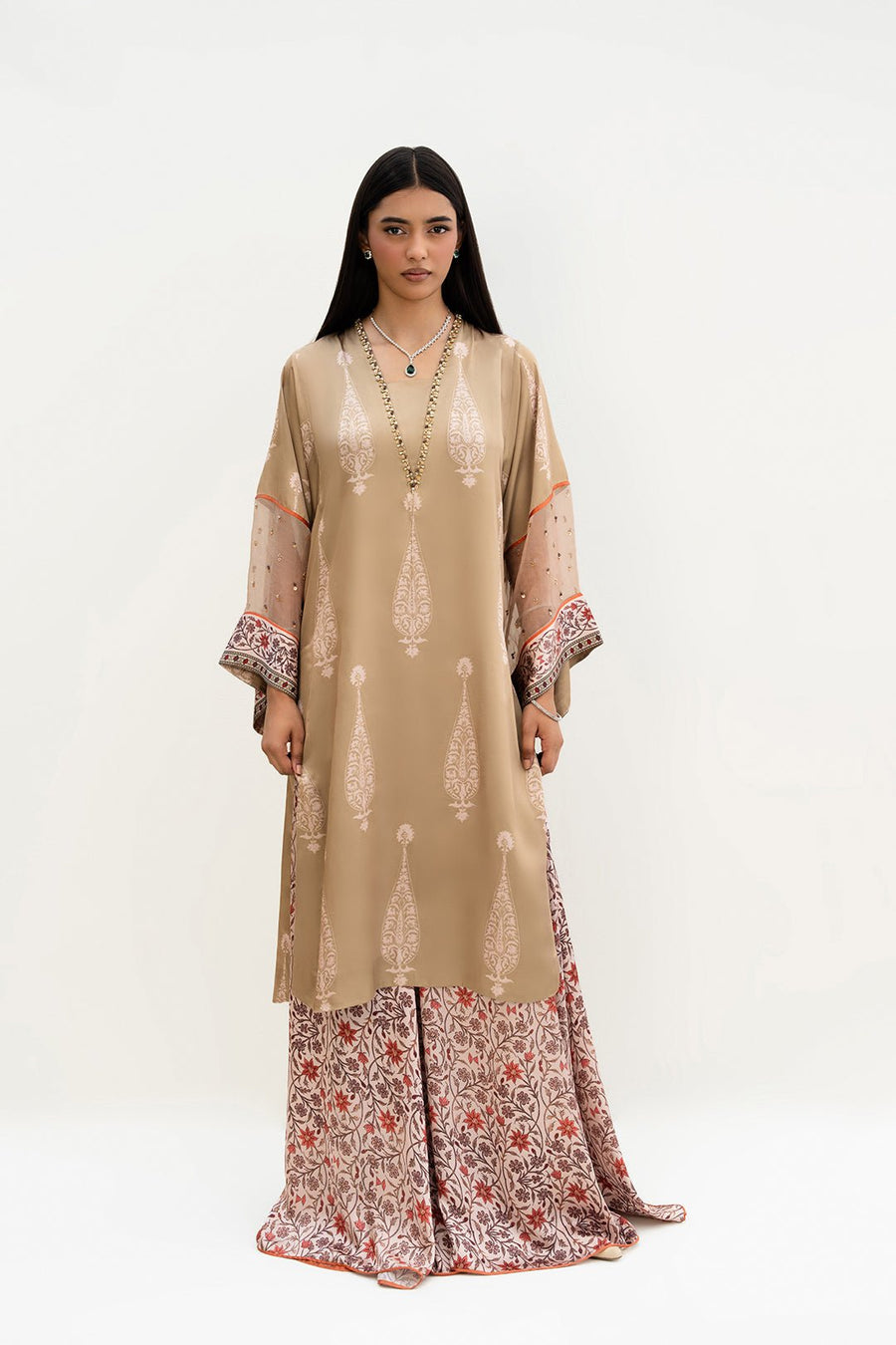 Full front view of a woman wearing beige printed kurta with floral printed palazzo pants and embellished neckline.