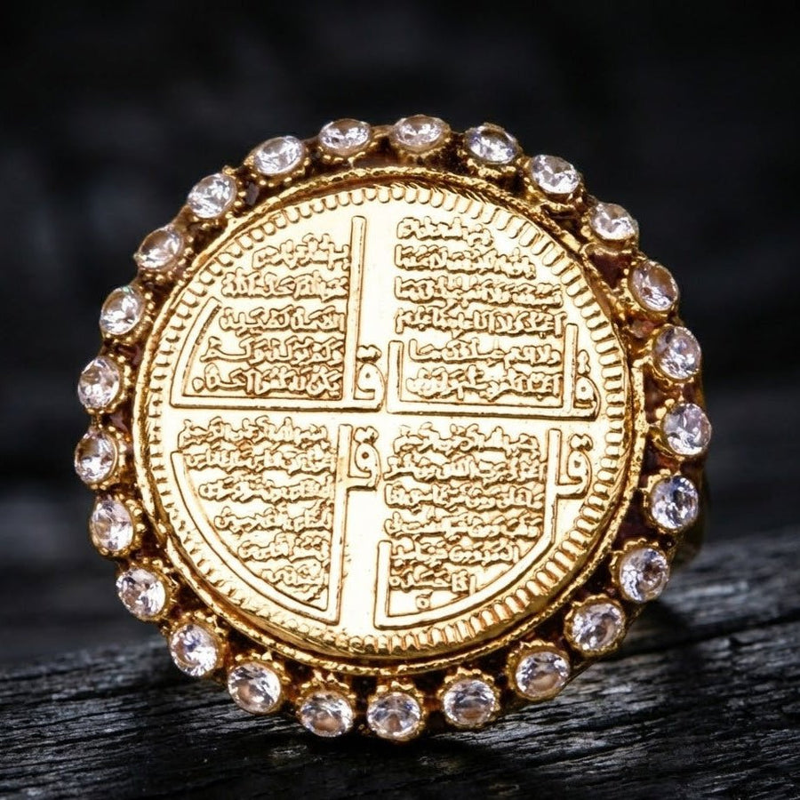 Detailed macro shot of gold ring engraved with four Surahs, surrounded by clear stones, on dark wood