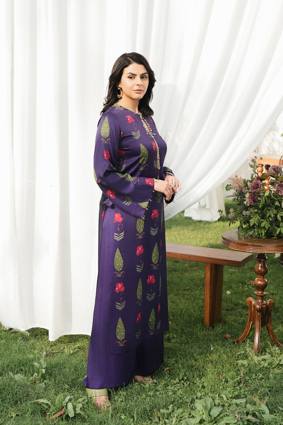 Side view of woman modeling the full-length straight purple floral kurta with matching silk pants outdoors