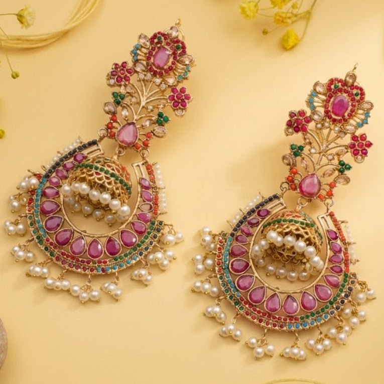 Close-up of exquisite traditional jhumka earrings with pink teardrop stones, multi-colored gems, and pearl drops on a warm yellow background