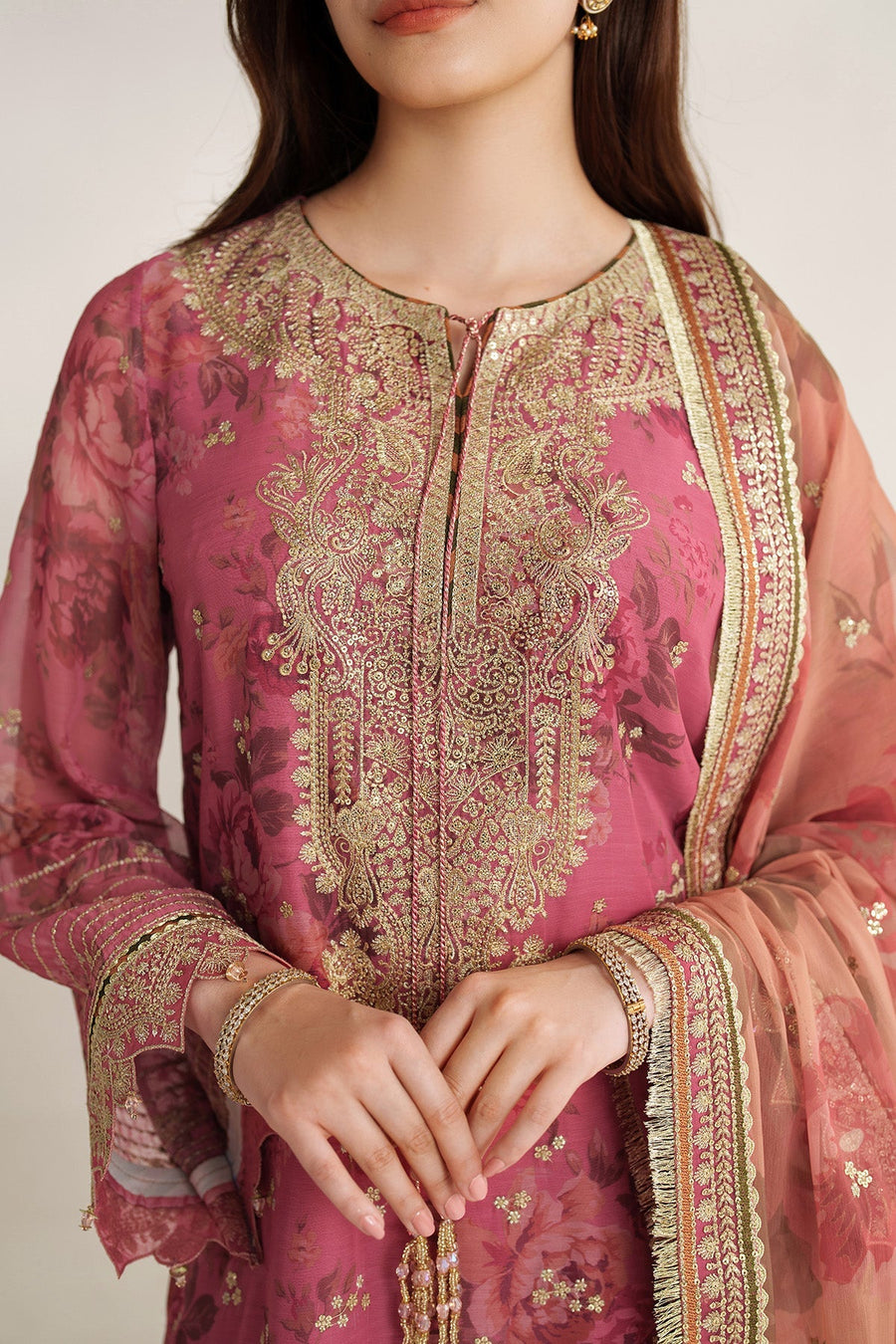 Close angle of gold embroidery and sequin work on sleeves and neckline of mauve-pink chiffon suit