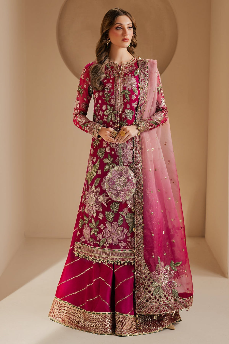Back view of model wearing embroidered deep magenta formal suit with keyhole back design and sheer pink dupatta