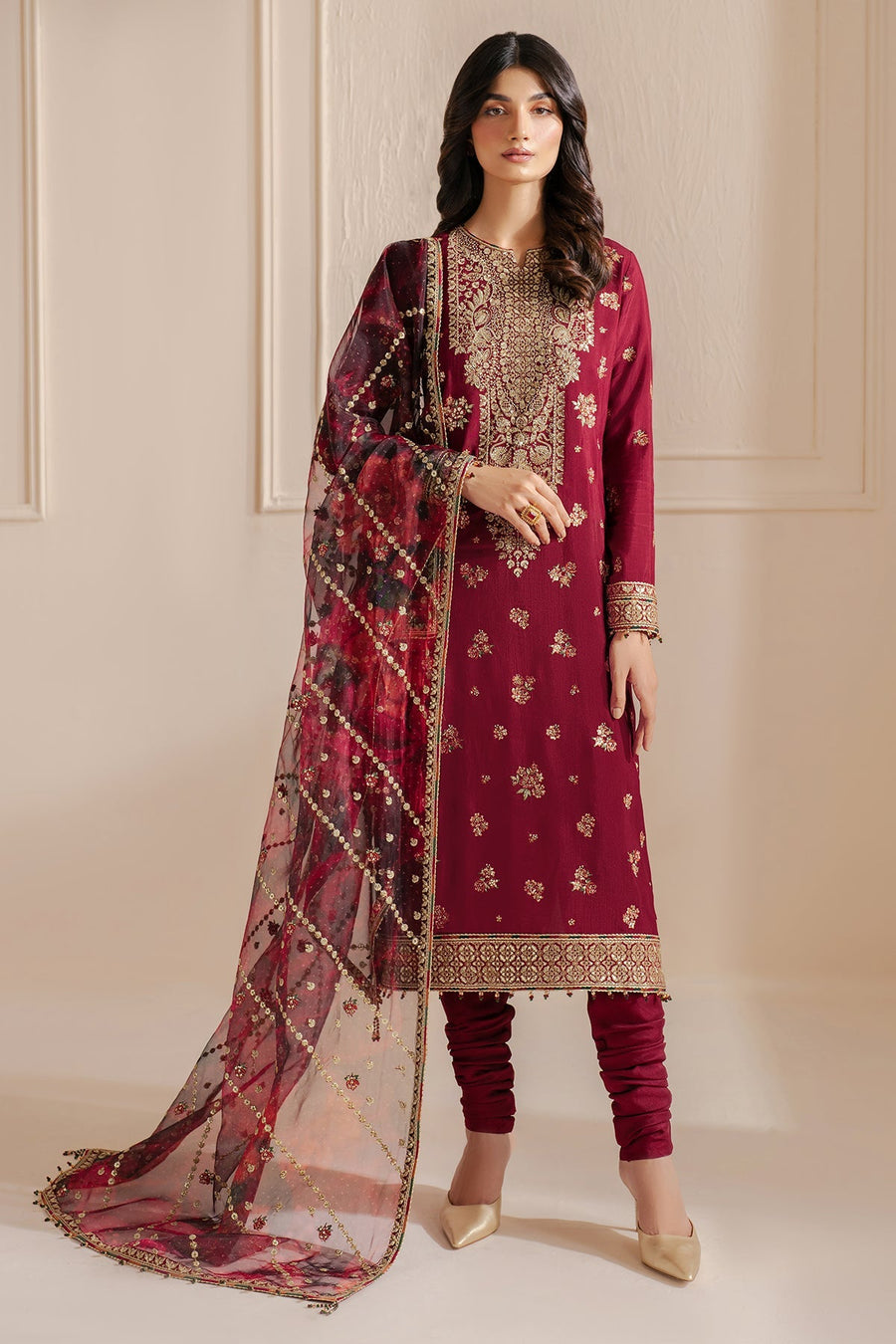 Close-up of the upper body of a woman wearing a deep maroon formal suit with ornate gold embroidery on the neckline and sleeves, highlighting the intricate threadwork and bead embellishments on the sheer organza dupatta.