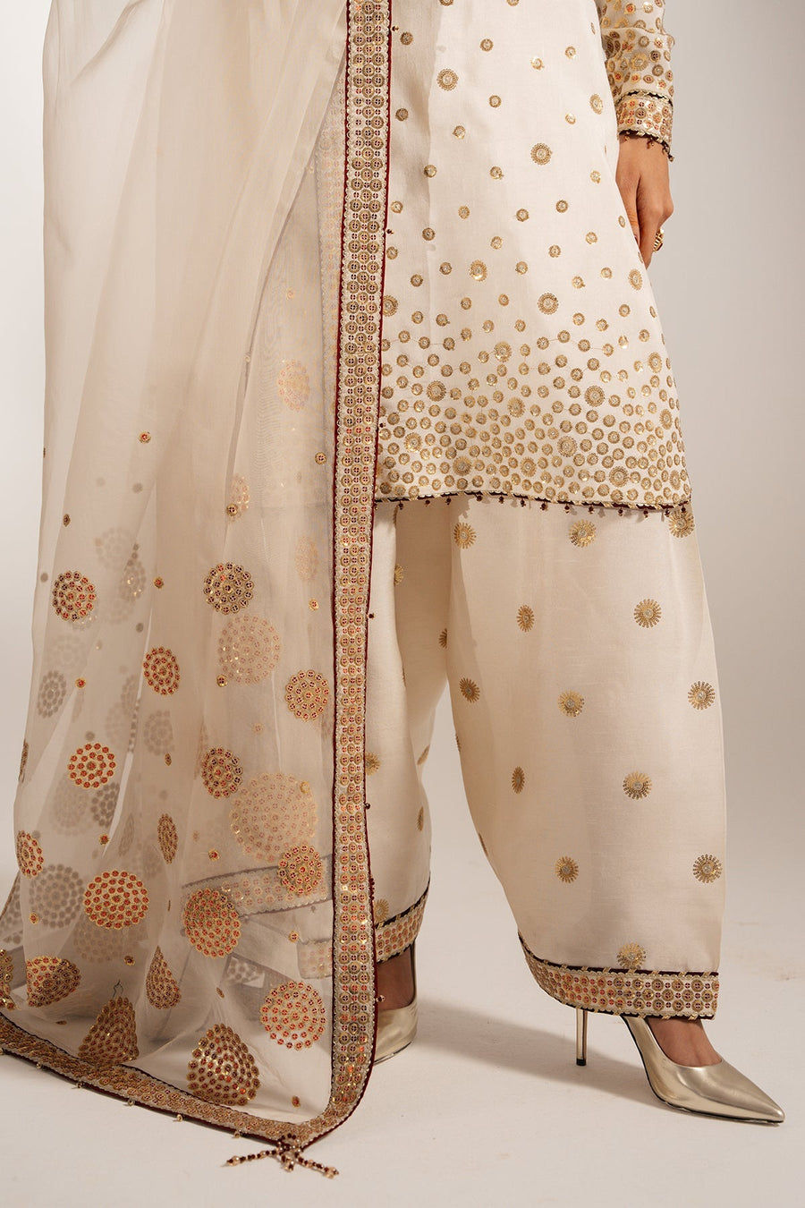 Model holding dupatta close to chest showcasing the intricate embroidery and fine fabric texture.