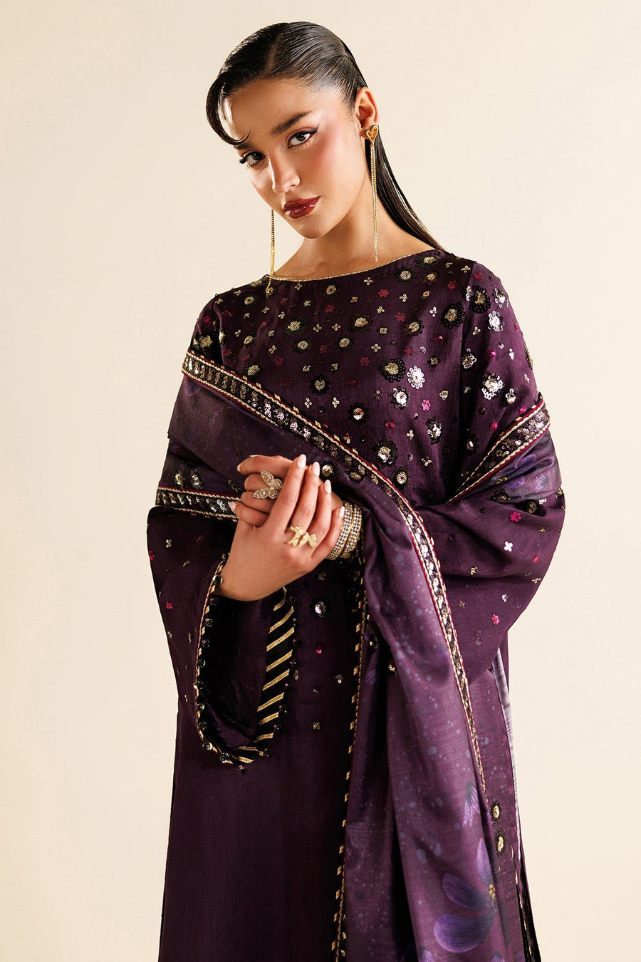 Detailed embroidery on sleeve cuffs with bead tassels against rich plum fabric