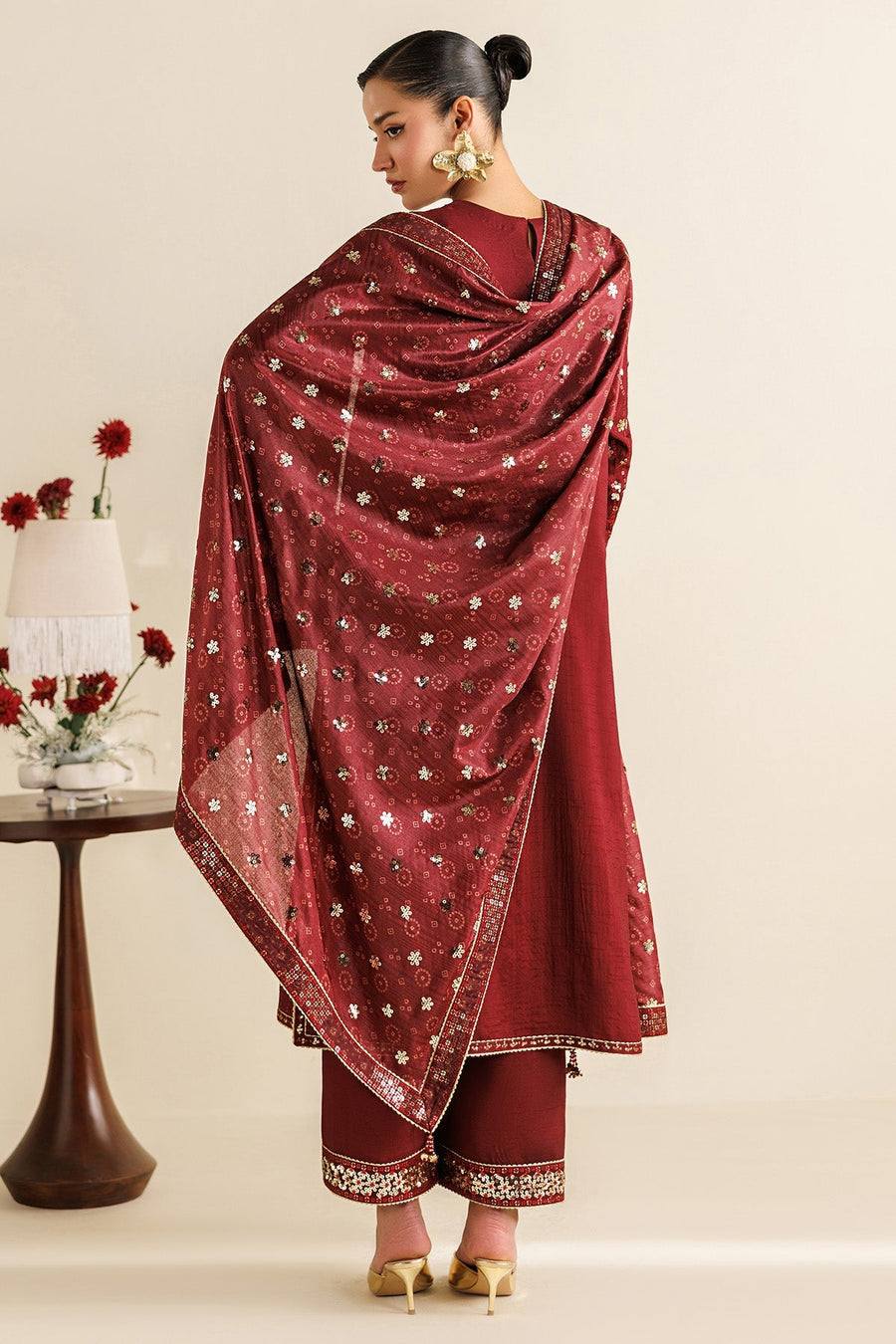 Back view of woman in maroon embroidered suit showcasing detailed dupatta design