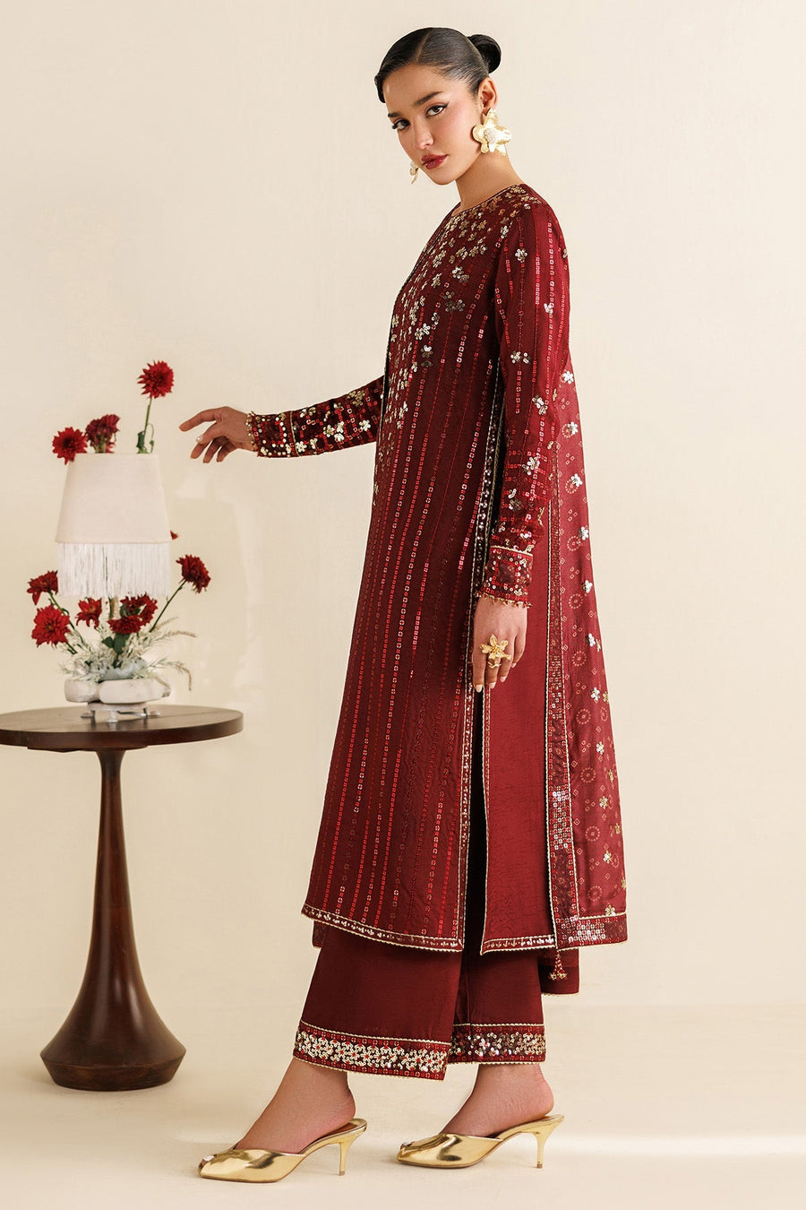 Close-up of woman adjusting red flower with detailed embroidery and sequins on sleeve and dupatta