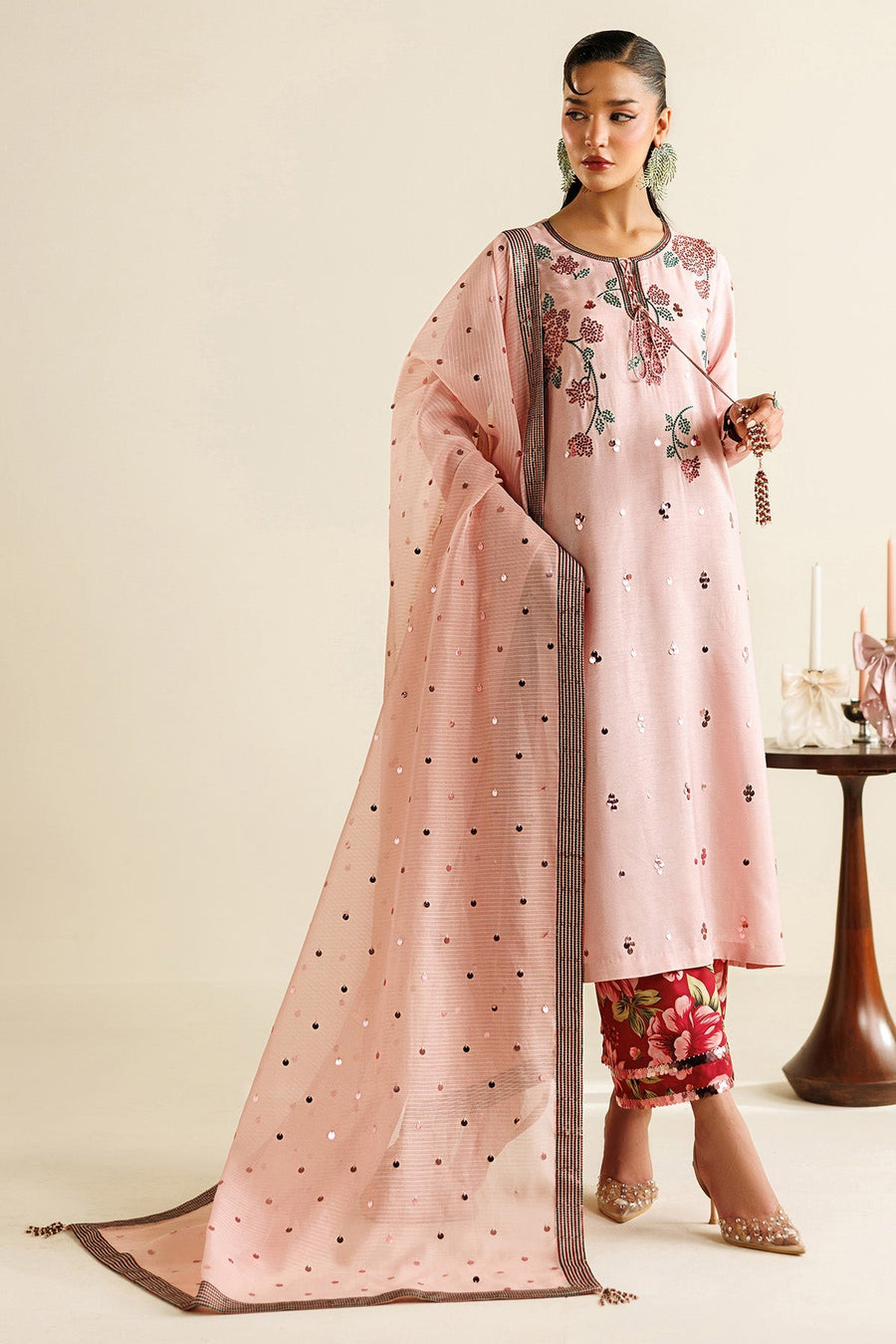 Close-up of woman holding red roses wearing pink embroidered shirt with delicate floral embroidery and sequins, and matching dupatta