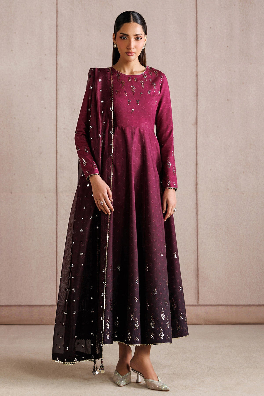 Woman wearing embroidered deep magenta Anarkali suit holding arms crossed in front, highlighting detailed sequin work