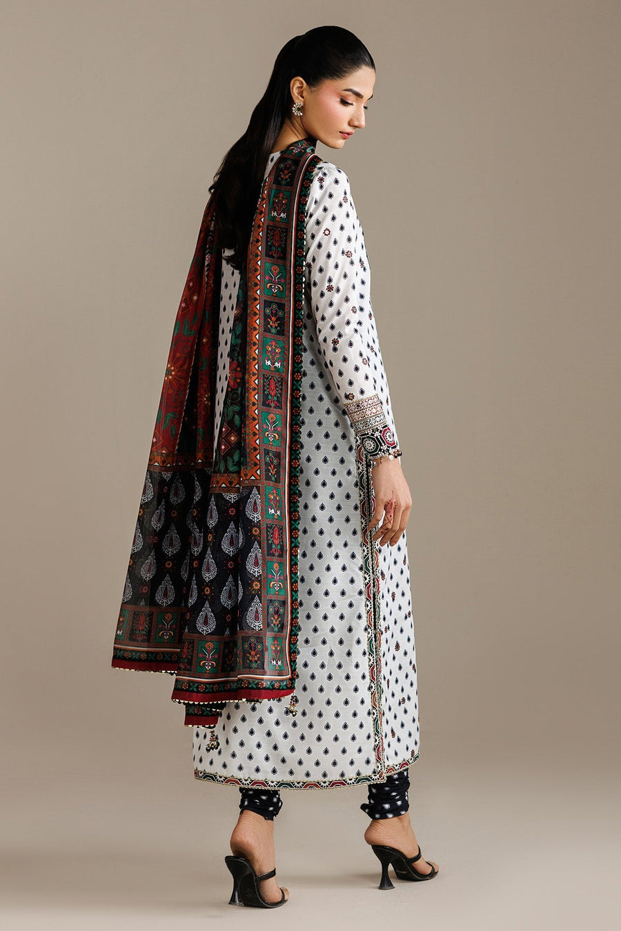 Back view of woman in white embroidered lawn kurta, showing side slits and detailed pattern on dupatta draped over shoulder.