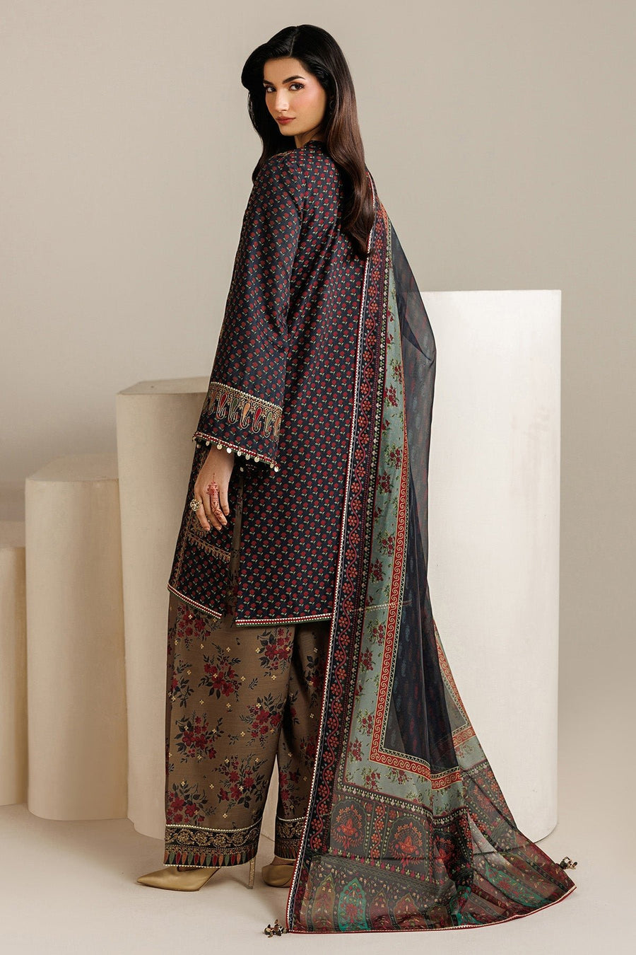 Back view of woman showcasing embroidered navy shirt and floral pants complemented by sheer printed dupatta