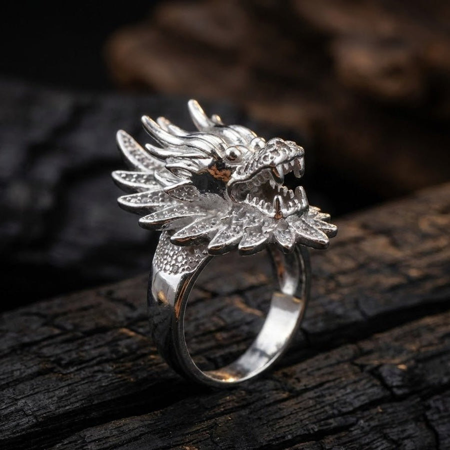 Silver dragon head ring photographed on textured dark wood background highlighting craftsmanship and shine