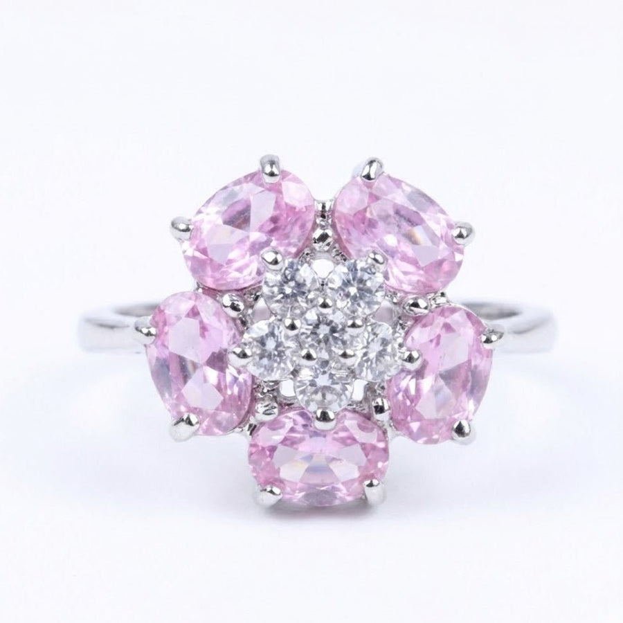 Close-up view of an elegant silver ring featuring a floral design with five pink oval gemstones surrounding central small clear stones.