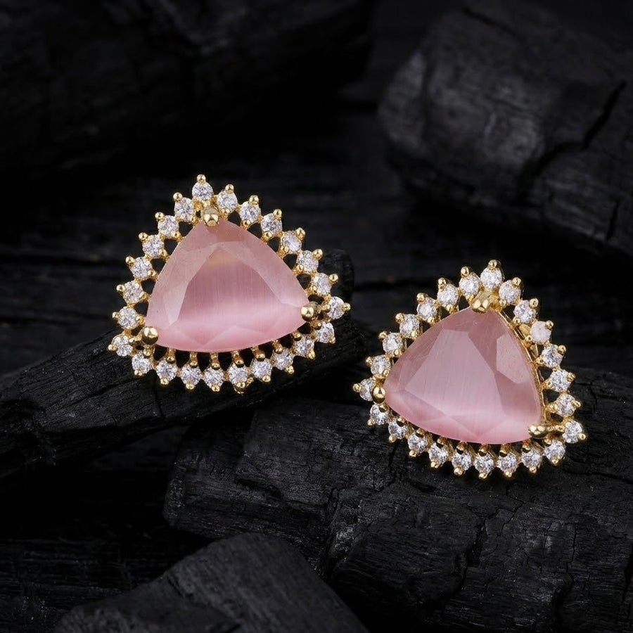 Soft pink trillion cut gemstone halo stud earrings placed on dark textured surface for contrast