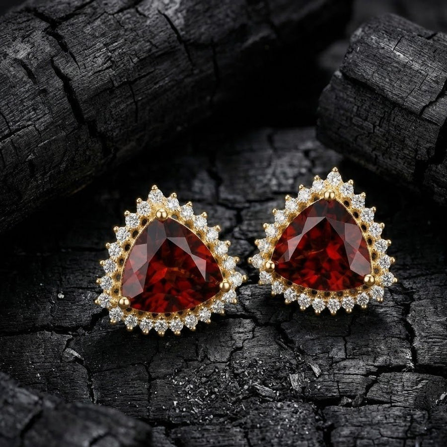 Deep red trillion cut halo stud earrings displayed on textured black surface highlighting sparkle