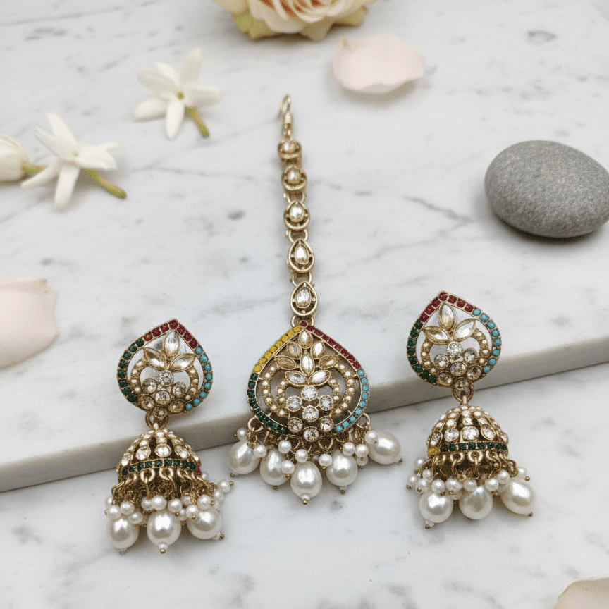 Majesty Pearl Drop earrings and maang tikka arranged on white marble with flowers and stone for elegant presentation