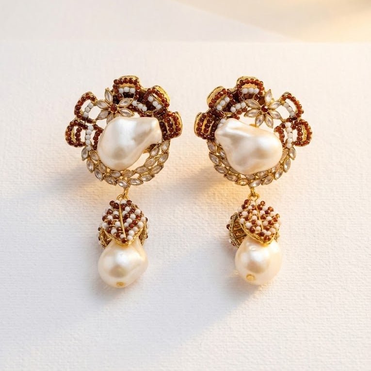 Ruby red pearl drop earrings photographed on light fabric surface