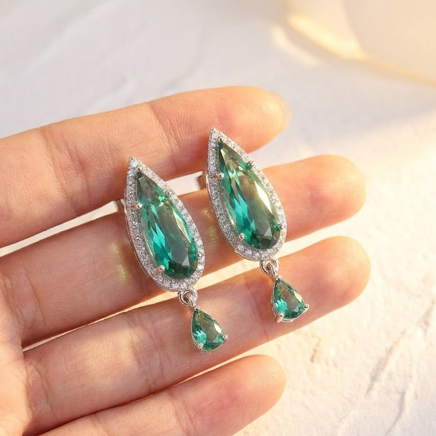 Green crystal earrings shown held in hand under natural light showcasing sparkle and size