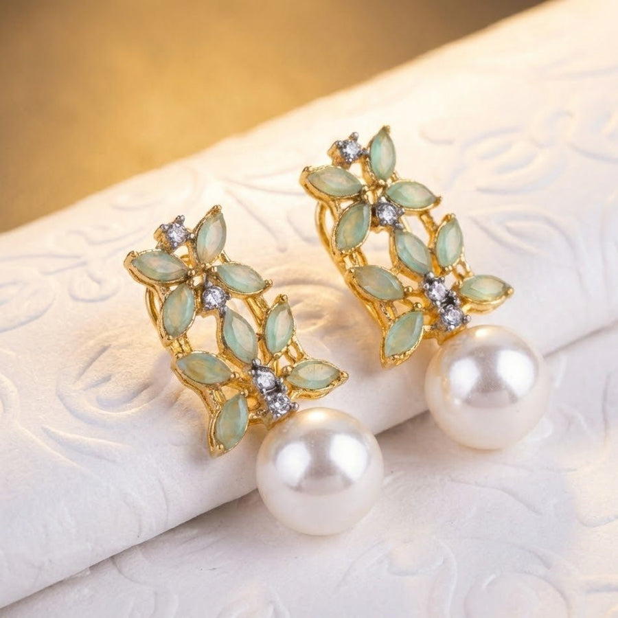 Pearl drop earrings settled on beige textured backdrop emphasizing refined details
